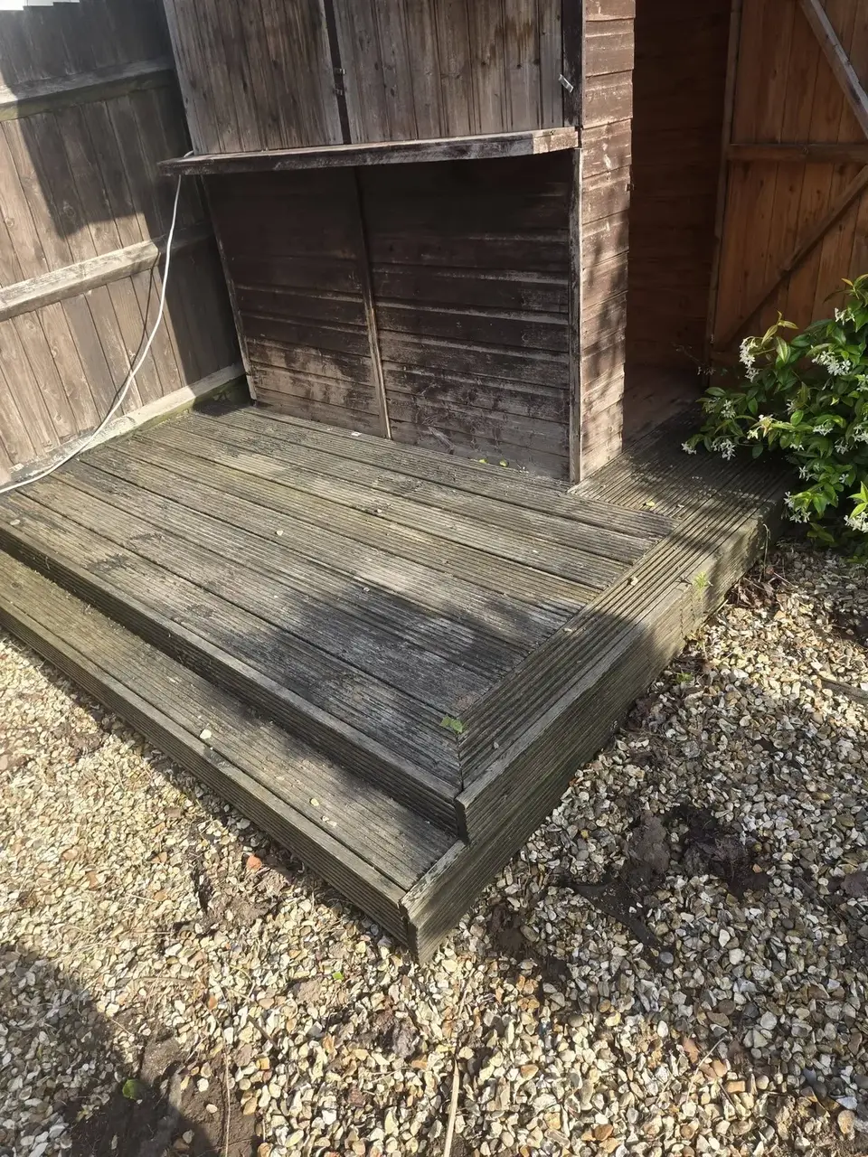 Garden decking and steps before cleaning, weathered grey and darkened with organic growth