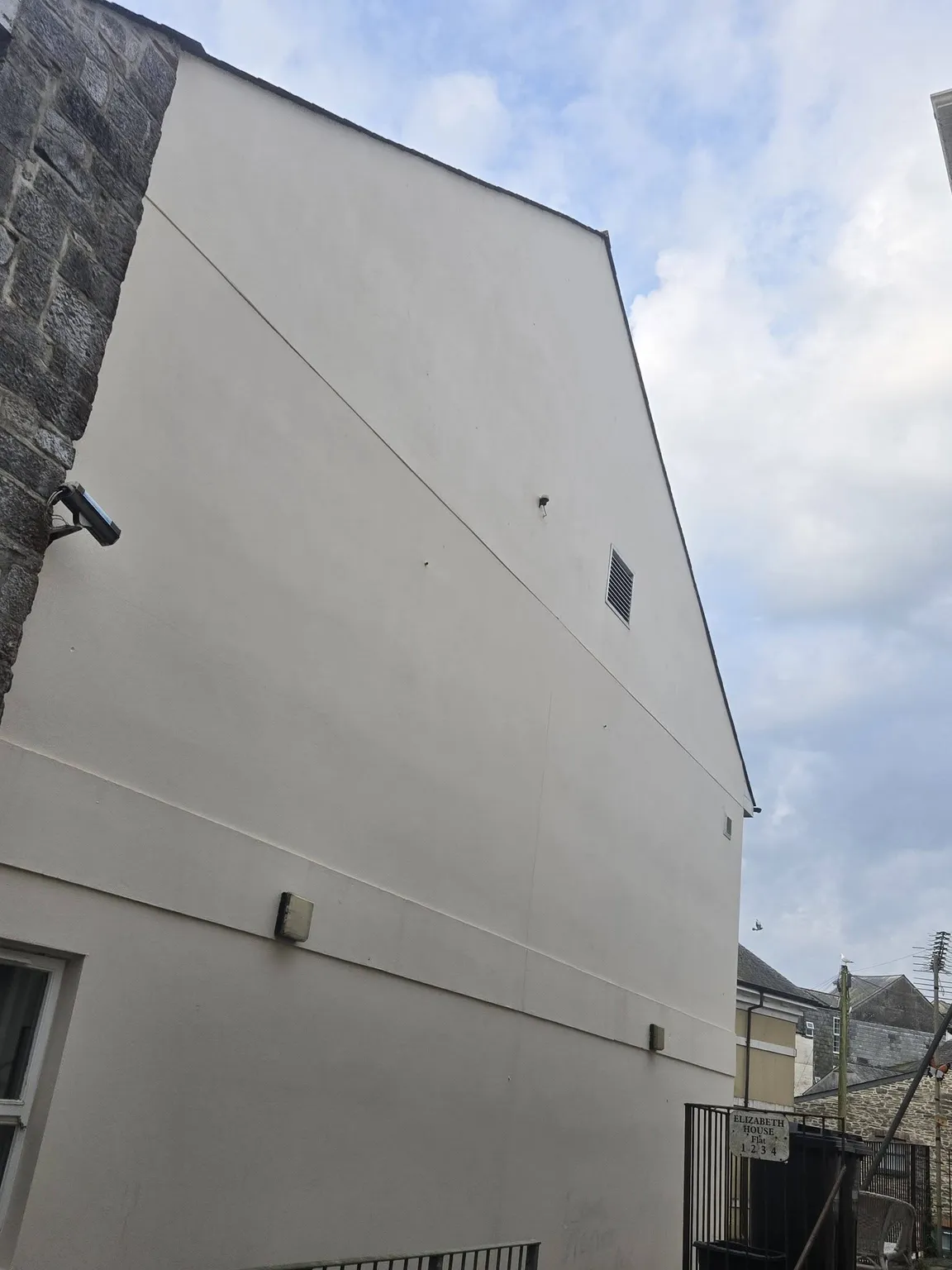 The same rendered gable end after cleaning, restored to a bright even white